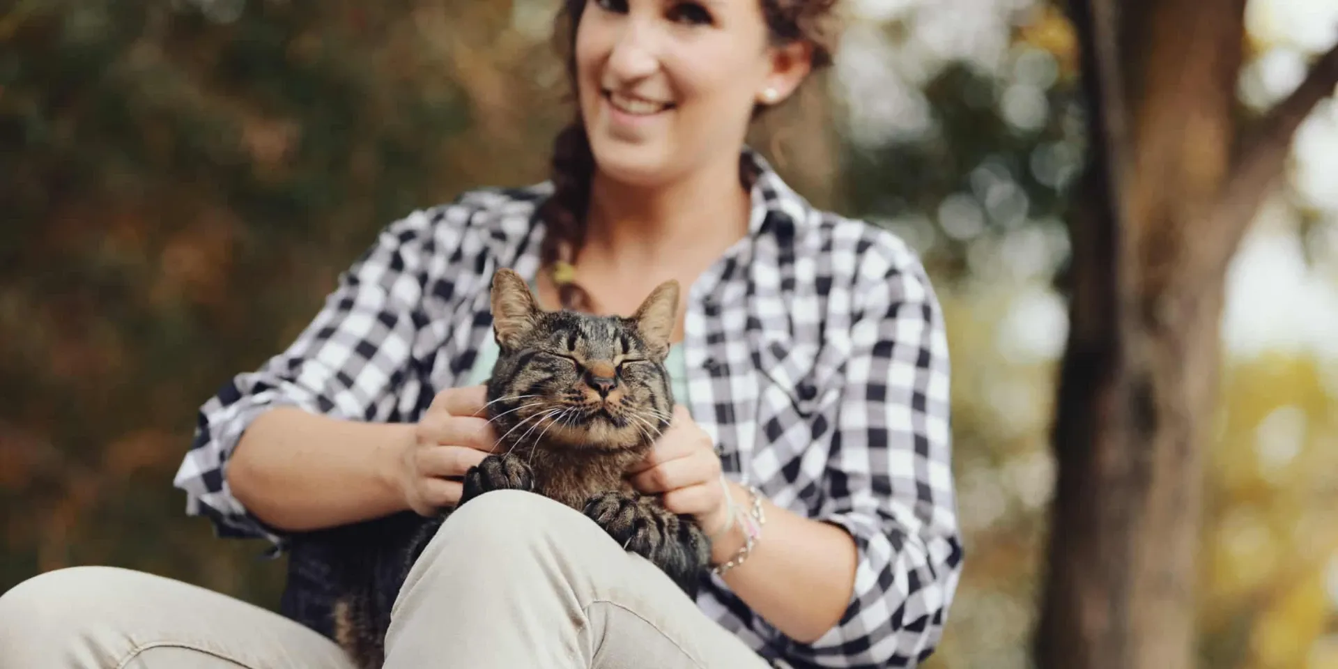 A woman sitting on a bench holding a cat.