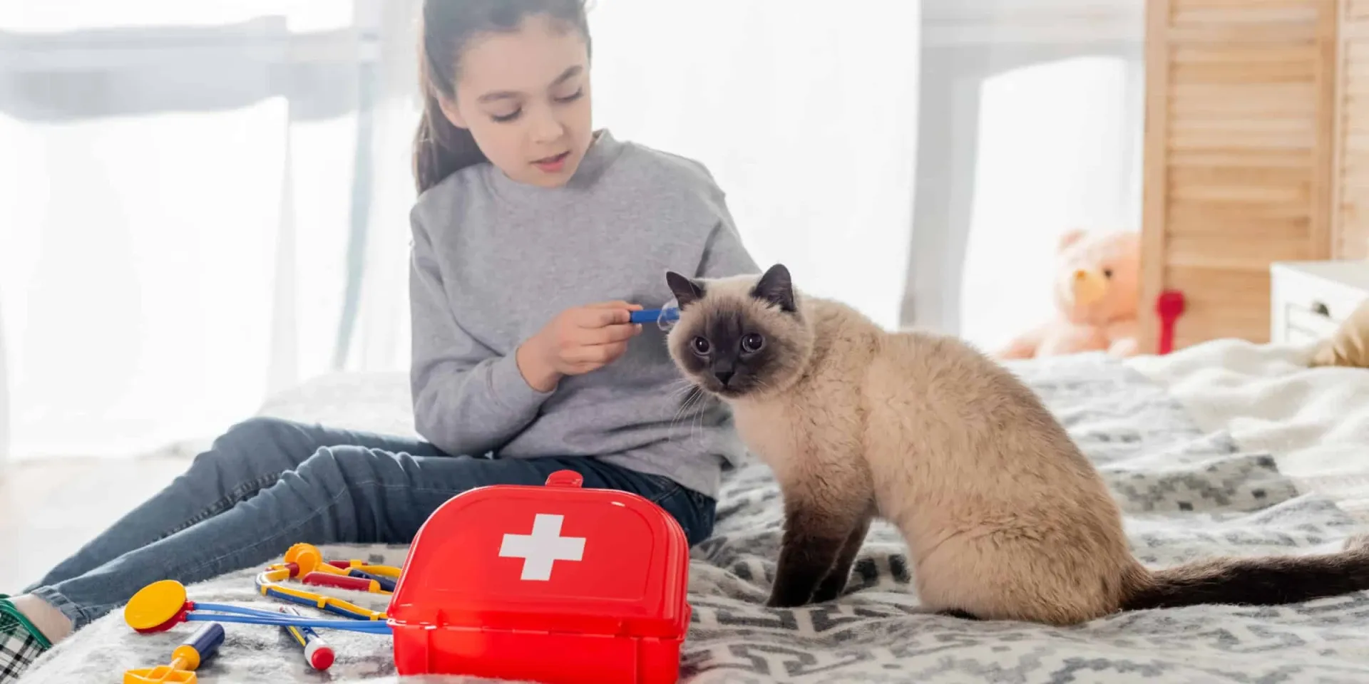 A girl is sitting on a bed with a cat next to her.